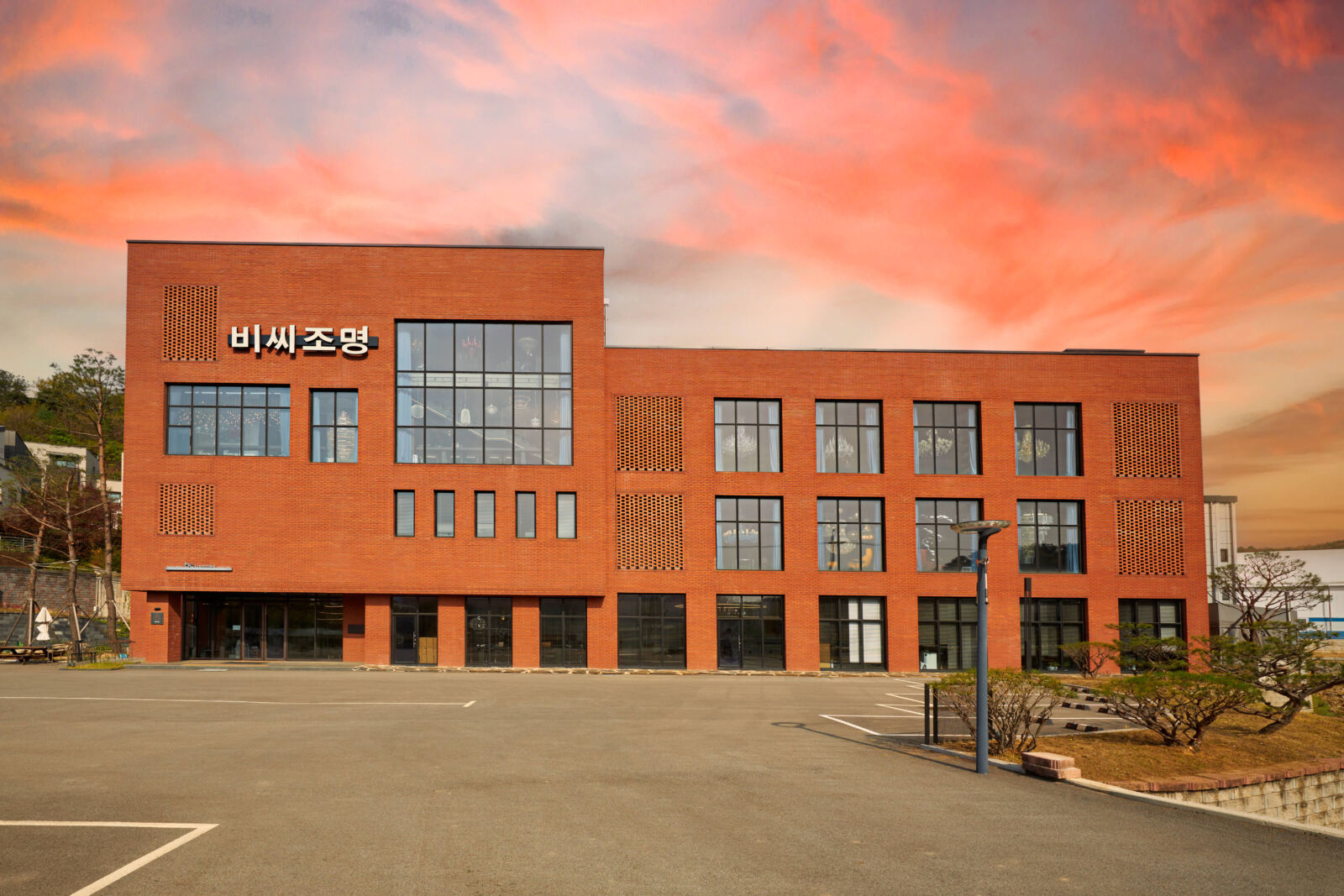 비씨조명 간판을 단 붉은 벽돌 3층 건물 정면과 앞의 주차장