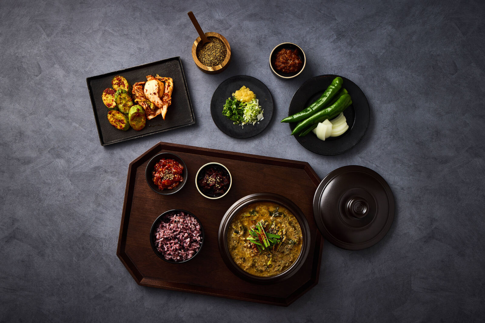 위에서 내려다본 추어탕 한 상, 흑미밥과 오이무침, 포기김치, 풋고추가 함께 놓였다