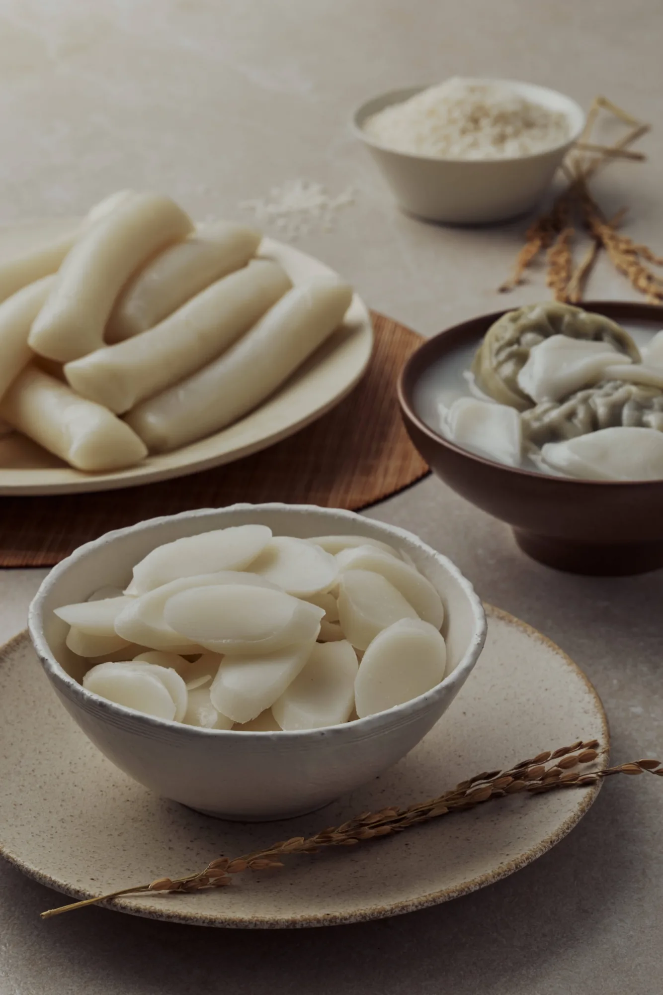 어슷 썬 흰 떡국떡을 수북이 담은 사발, 뒤에 가래떡 접시와 쌀가루